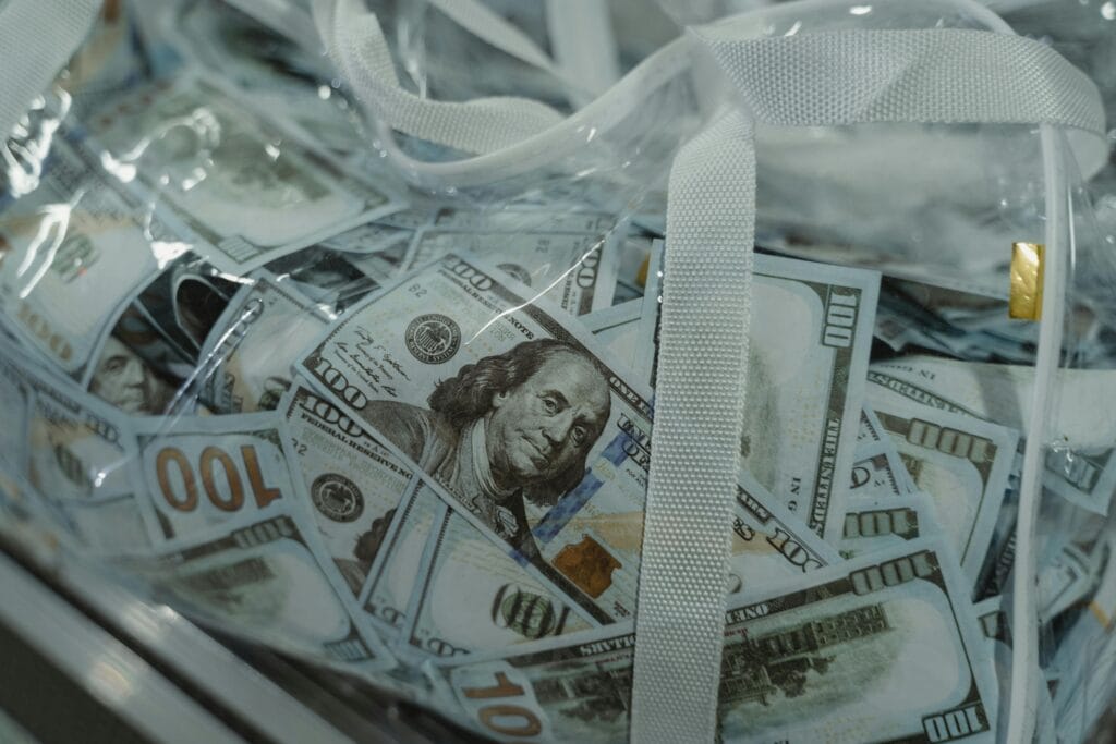 Close-up of transparent bag containing hundred dollar bills, symbolizing wealth.